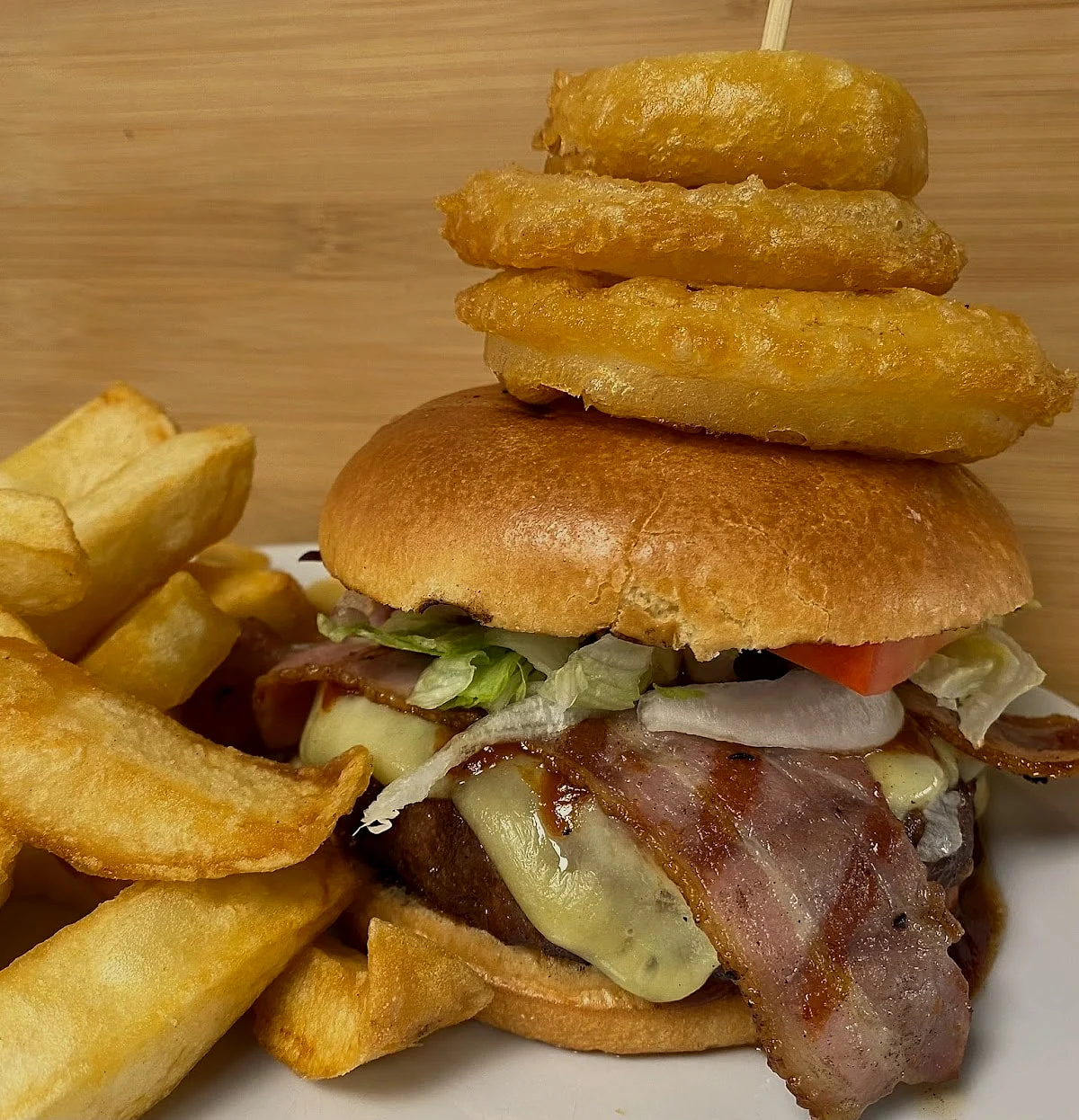 Bacon cheeseburger topped with a stack of onion rings, with chips