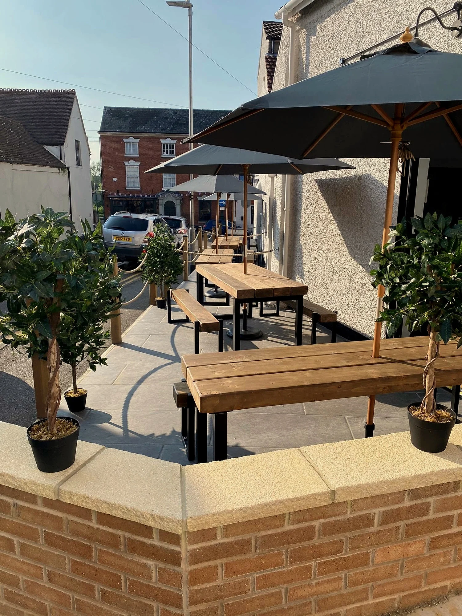 The terrace in sunshine, wooden tables under parasols